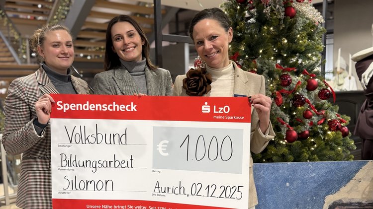 Drei Frauen, sie halten einen symbolischen Scheck vor sich