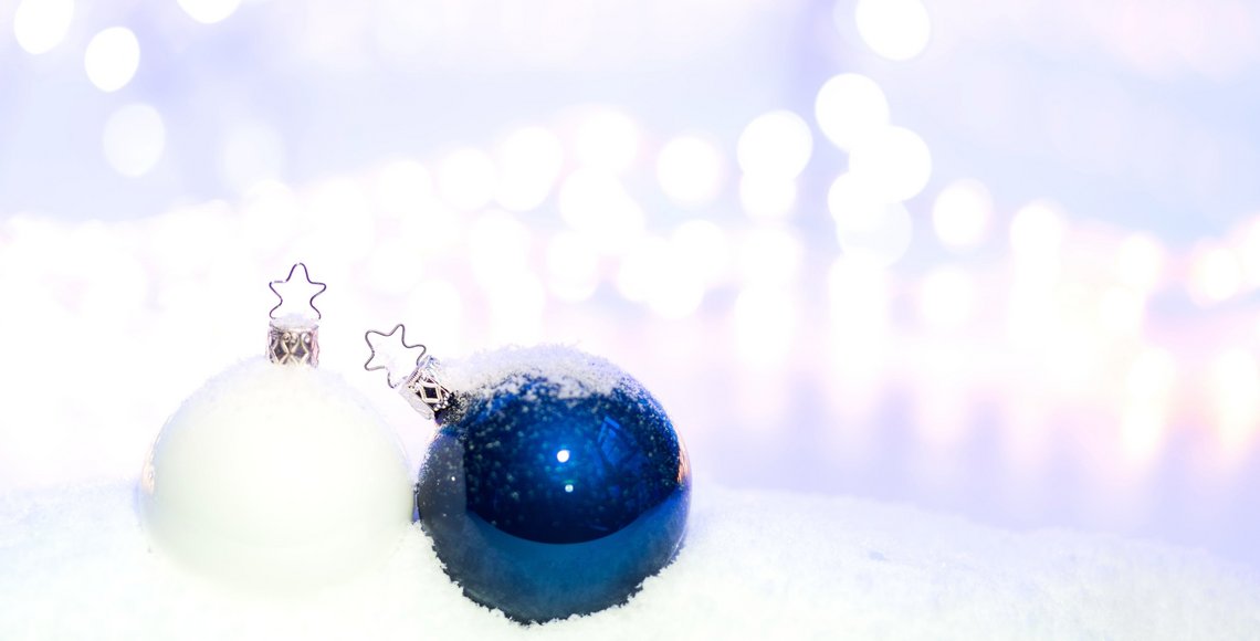 Eine weiße und eine blaue Christbaumkugel vor einem weißen Hintergrund