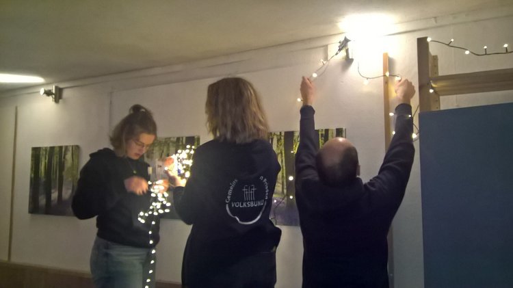 Drei Personen befestigen Lichterketten.