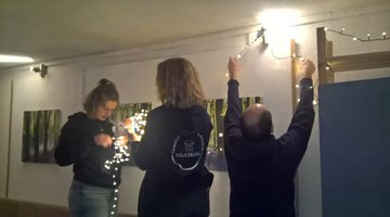 Drei Personen befestigen Lichterketten.