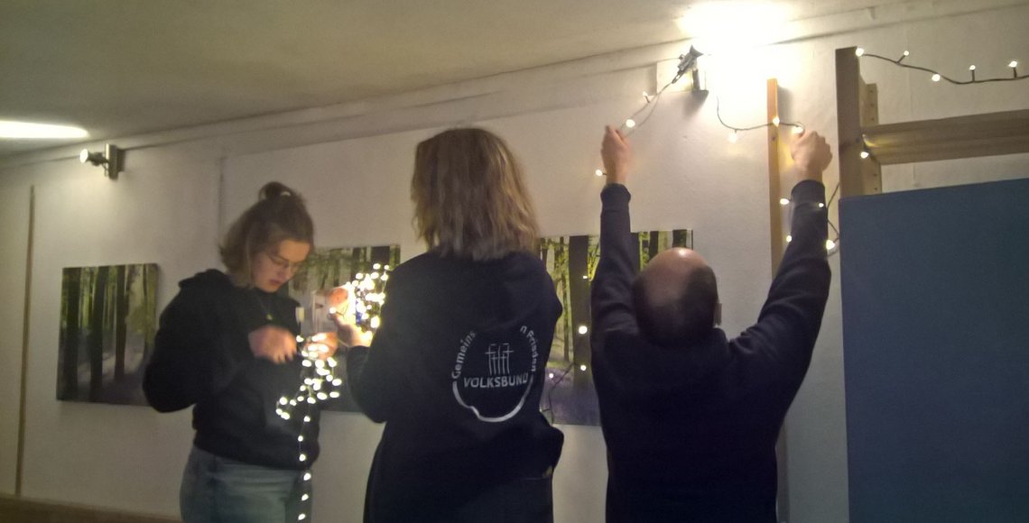Drei Personen befestigen Lichterketten.