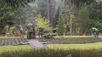 Mehrer arbeitende Personen in Uniform auf einem Friedhof