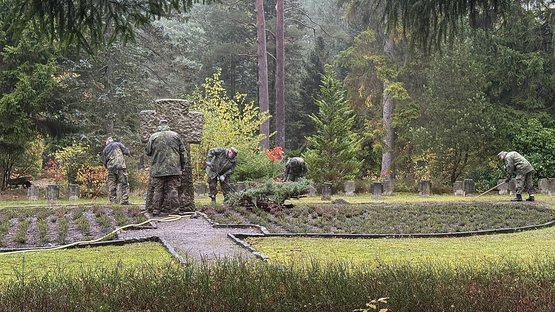 Mehrer arbeitende Personen in Uniform auf einem Friedhof